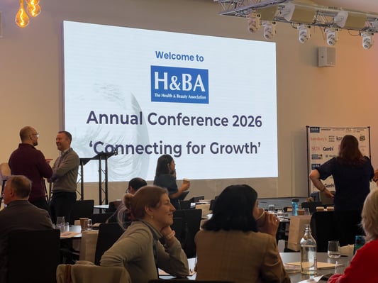 Attendees networking at the Health & Beauty Association Annual Conference 2026, featuring a stage with large display screens.