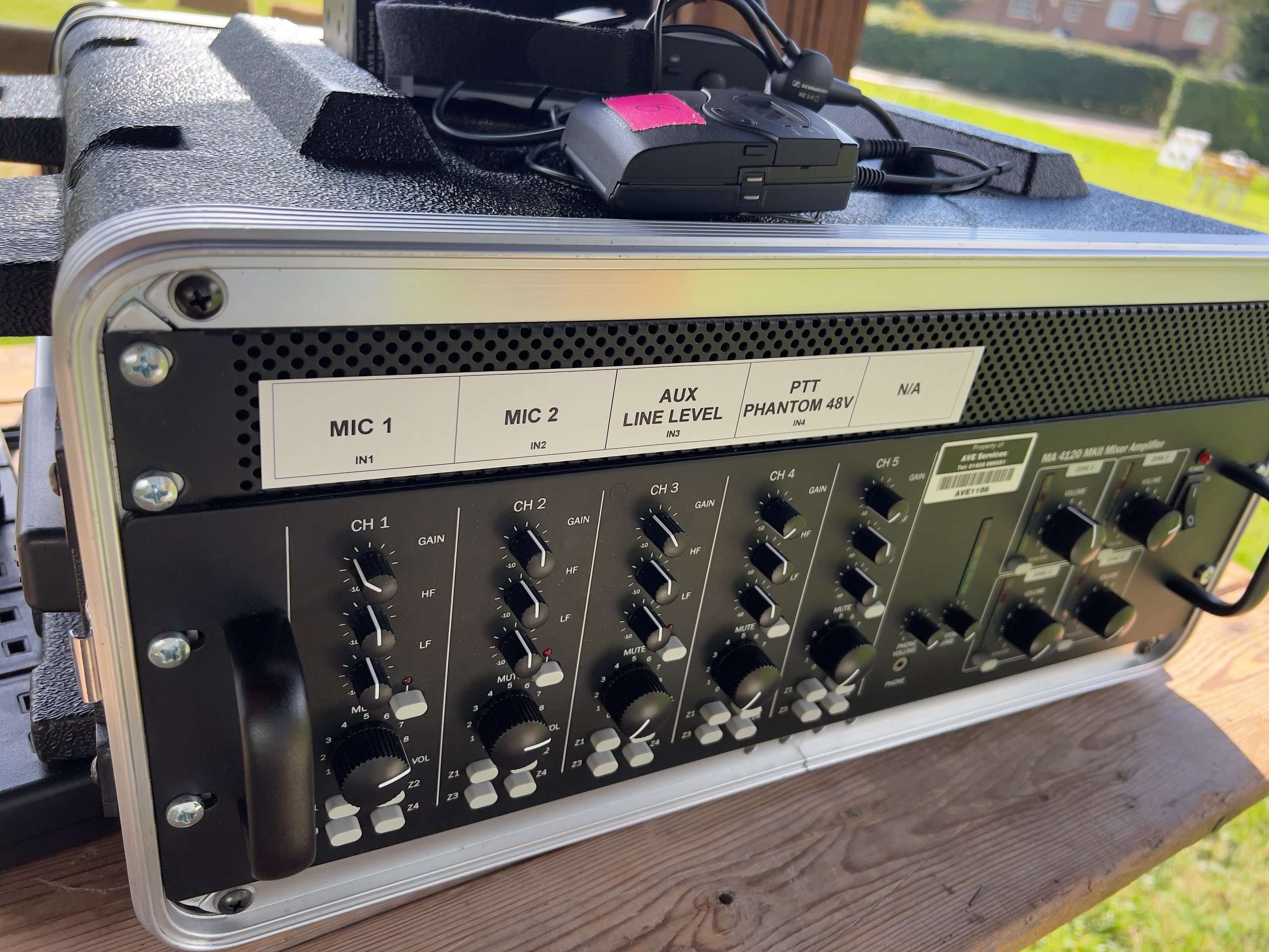 Audio mixer setup with multiple channel controls and mic inputs for outdoor event sound management.