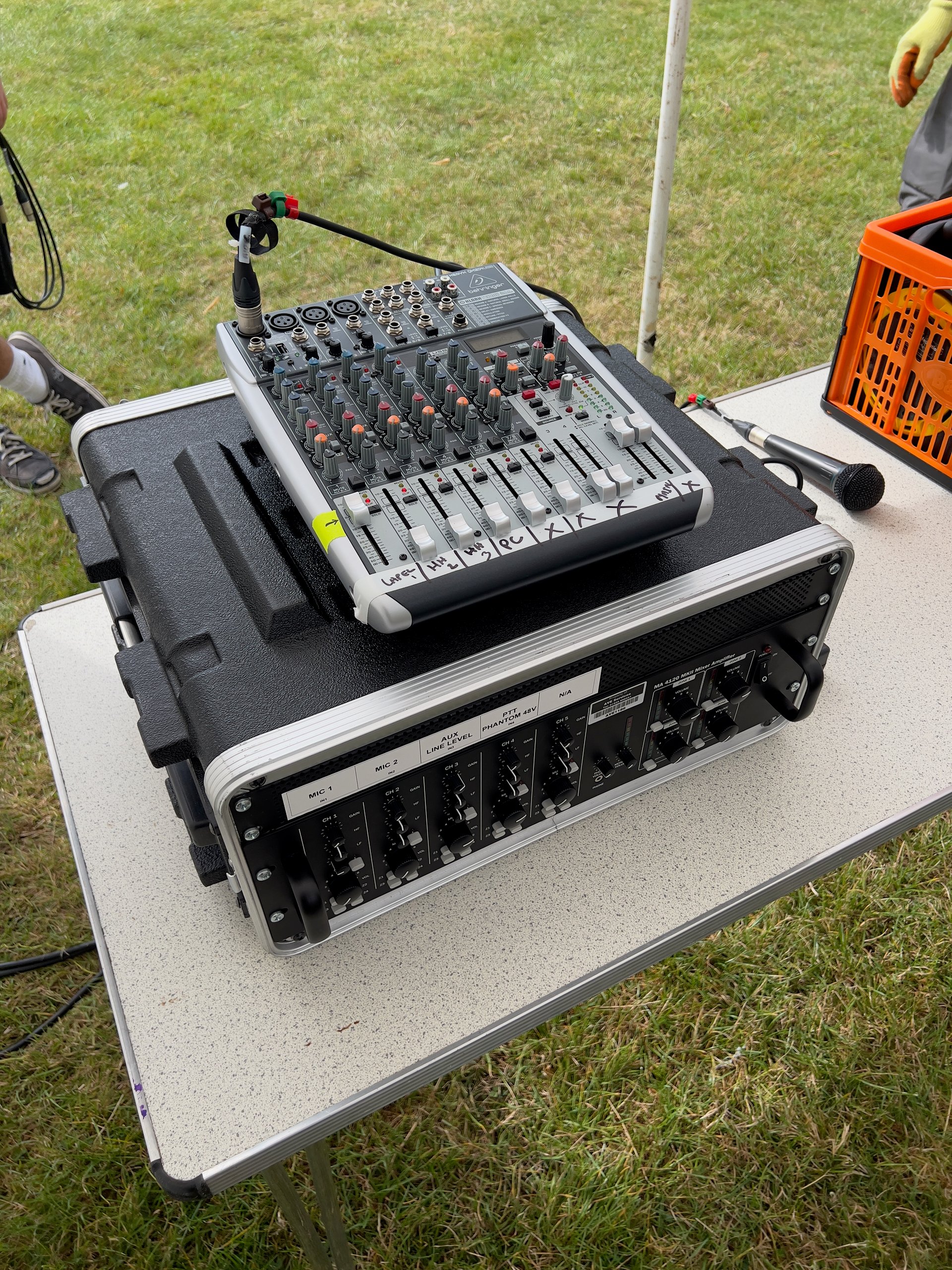 Audio mixer and amplifier setup on outdoor event table, ready for sound production.