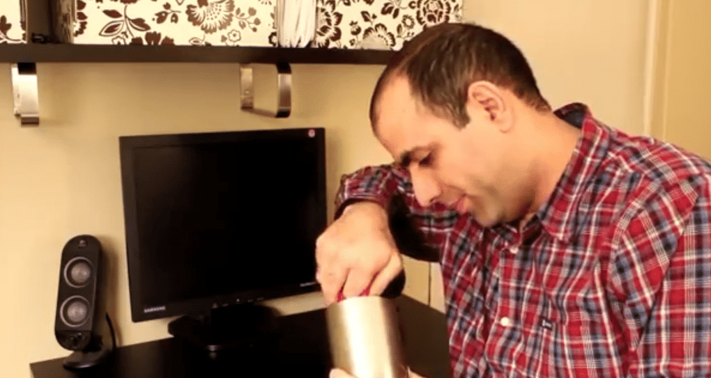 Person setting up audio equipment on a desk, adjusting a speaker near a monitor.