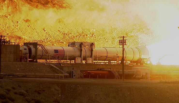 A powerful rocket booster test igniting in a desert testing facility, highlighting intense flame propulsion and engineering precision.
