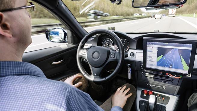 Person using autonomous driving technology on a highway, viewing navigation data on a dashboard screen.