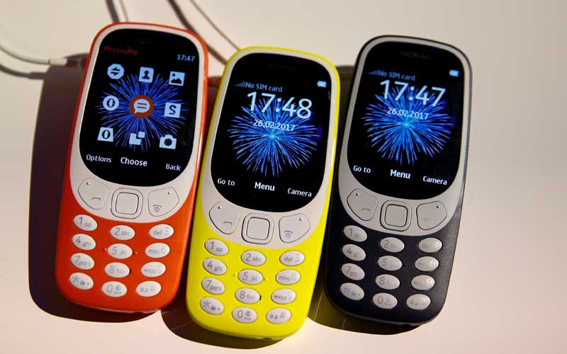Three Nokia feature phones displayed with colorful casings, showing fireworks on screens, used in mobile technology demonstrations.