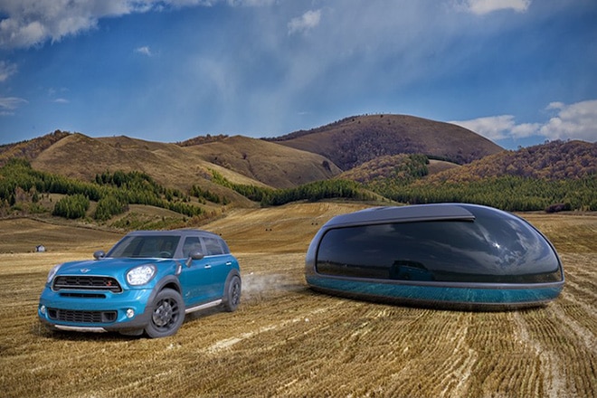 A blue SUV and a futuristic pod are parked in a vast, open countryside field under a clear sky.