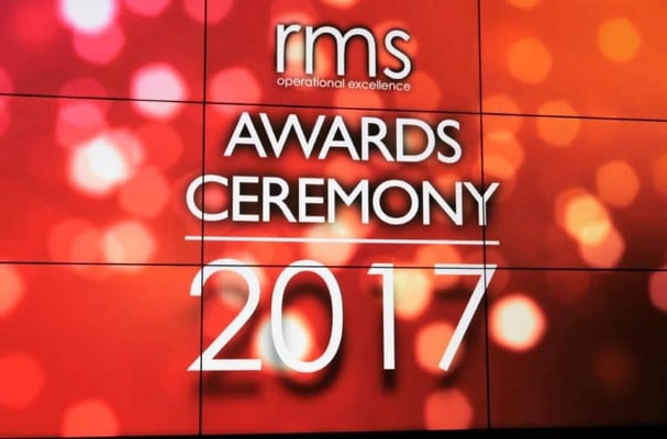 Awards ceremony backdrop with vibrant orange lighting and 2017 displayed on stage screens for a corporate event.