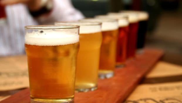 A selection of beers in a tasting flight, displayed on a wooden paddle at a corporate event’s refreshment area.