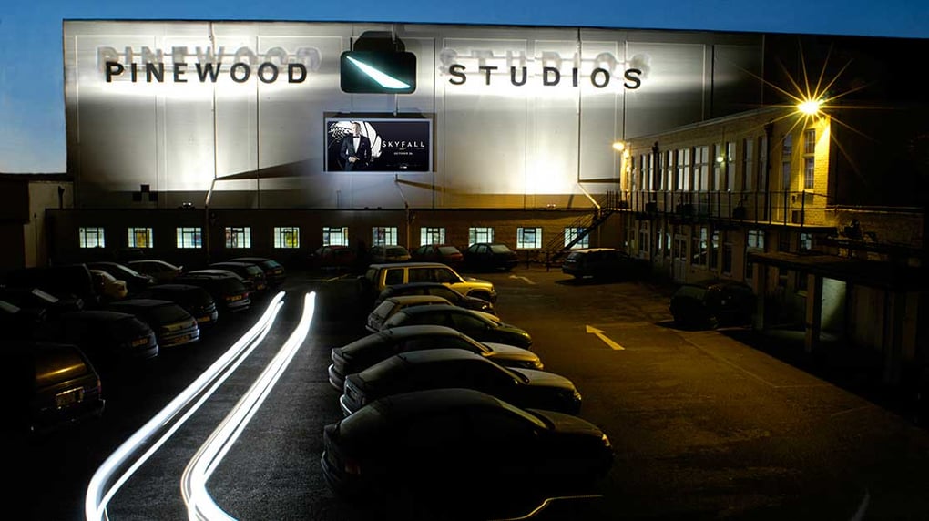 Pinewood Studios building exterior with illuminated signage and parking lot at dusk, highlighting cinema production facility.