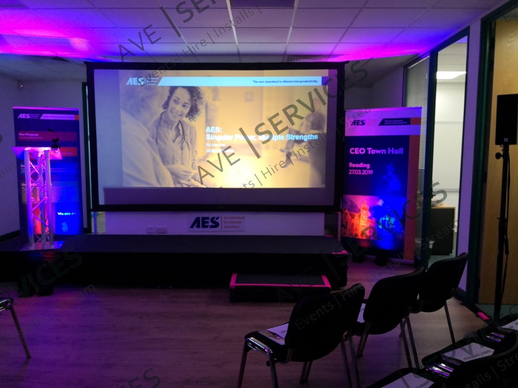 Staged corporate setup with projector screen, podium, and chairs at a CEO Town Hall event in Reading, UK.