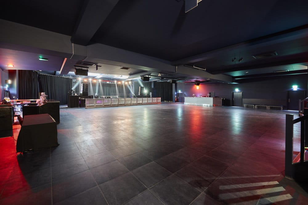 Spacious event venue setup with professional stage, lighting, and sound equipment for a corporate conference or awards night.