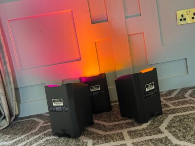 Uplights casting vibrant orange and pink hues on a textured conference room wall, enhancing event ambiance.