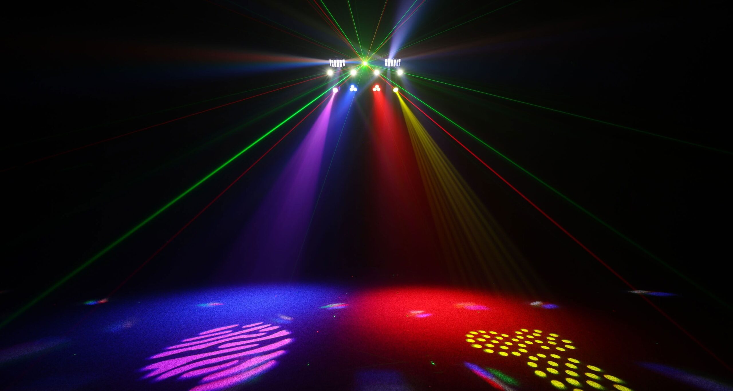 Dynamic stage lighting with colorful beams and patterned spotlights at an event venue.