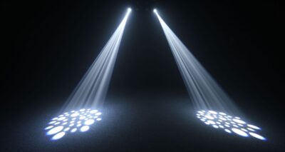 Bright stage spotlights creating patterned beams for a live event setup in a dark venue.