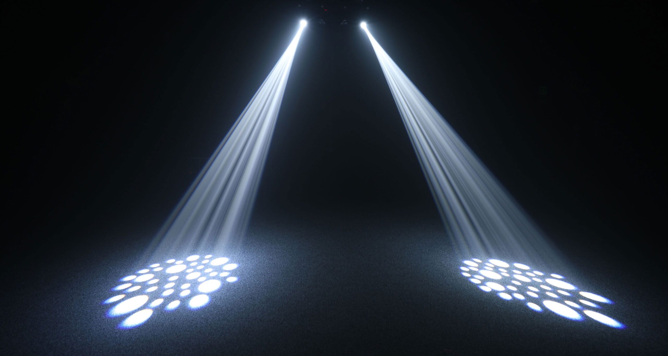 Bright stage spotlights creating patterned beams for a live event setup in a dark venue.