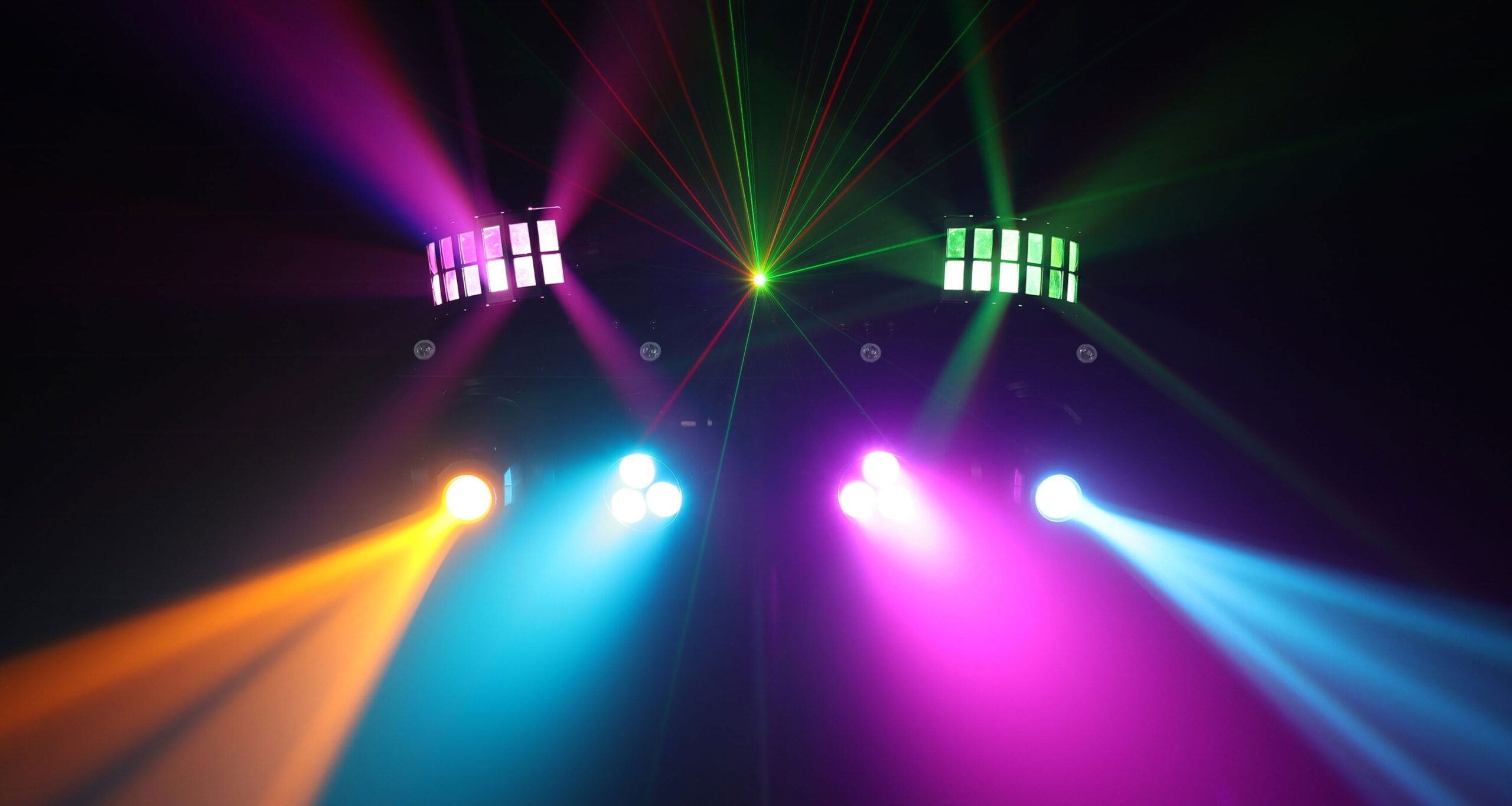 Colorful stage lighting setup with vibrant beams in orange, blue, pink, and green for a dynamic event atmosphere.