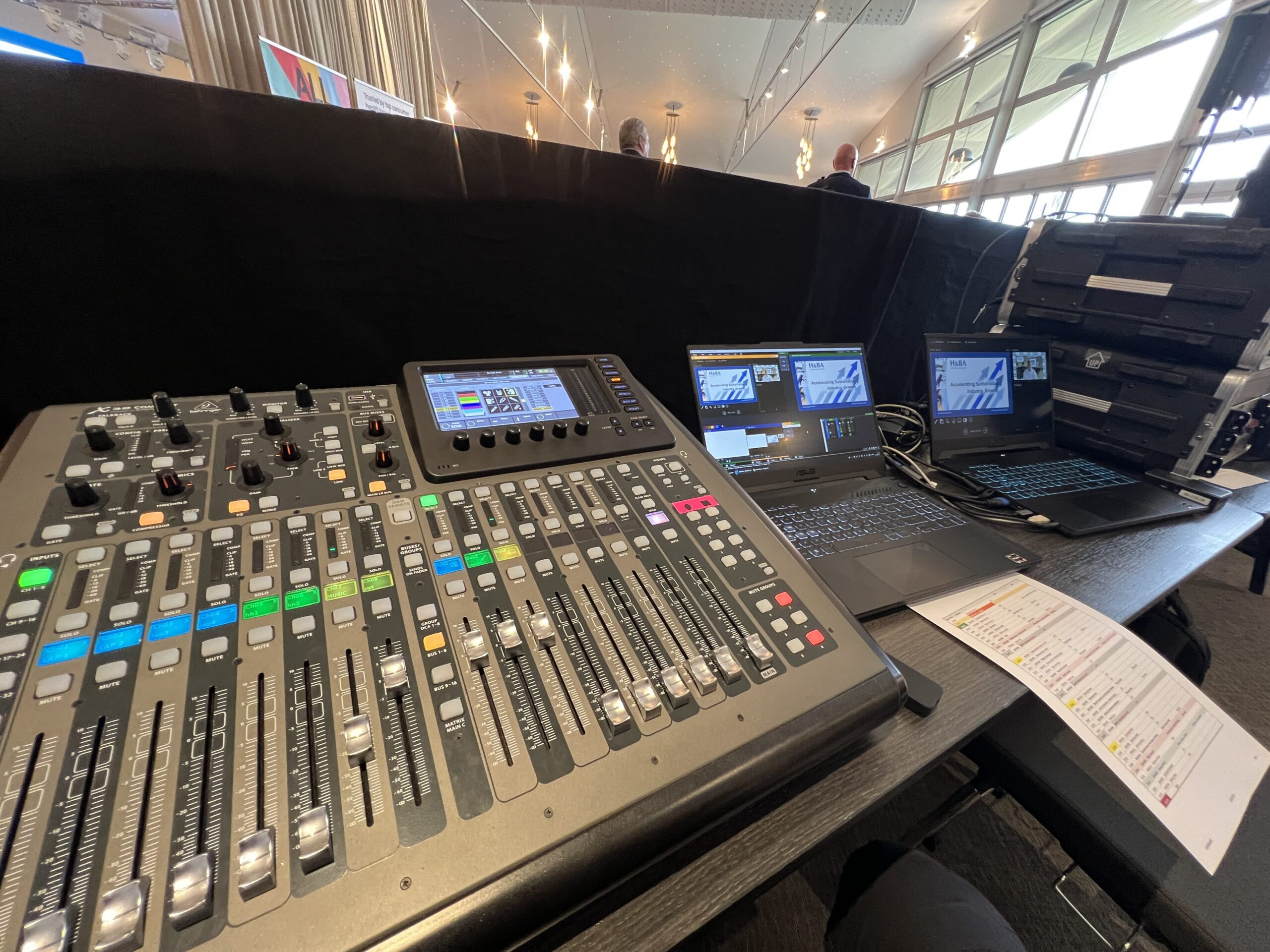 Audio mixing console and laptops set up for sound and video management at a corporate conference.